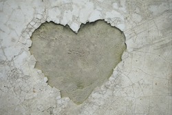 Heart shaped crack on the wall revealing the inner cement texture