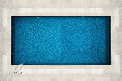 top view of a beautiful idyllic rectangular swimming pool with blue mosaic at the bottom