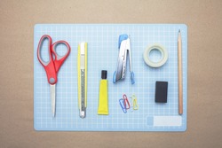Business concept:stapler,glue,scissor,cutter,tape,pen,pencil,clip,ruler,rubber, cutting mat and color pencil on brown paper background.Top view
