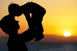 Father and little son - silhouettes on beach at sunset