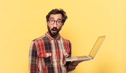 young crazy bearded man doubting or uncertain expression and a laptop