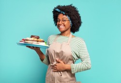young pretty afro woman baker with cakes