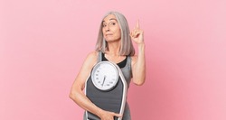 middle age white hair woman holding a weight scale. fitness and diet concept
