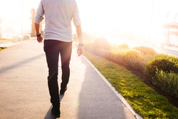 low section of a man walking in a sunny bright day
