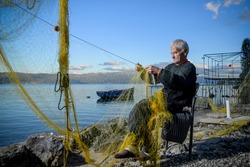 Senior fisherman holding fishing net near the beach. Fisherman hands close up. A fisherman preparing the fishing net