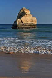 Big sea stack remaining from a rock formation in the water detached from the adjacent cliff that shelters the Praia dos Tres Castelos-Three Castles Beach on its north side. Portimao-Algarve-Portugal.
