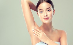 Young woman holding her arms up and showing underarms, armpit smooth clear skin .Girl showing clean armpit .Beauty portrait.Epilation and depilation of hair . 