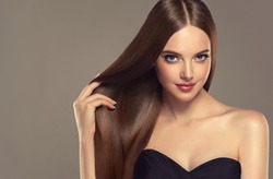 Beautiful model girl with shiny brown and straight long  hair . Keratin  straightening . Treatment, care and spa procedures. Smooth hairstyle. Care and beauty  products .
