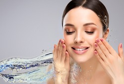 Beautiful spa woman with water splashes. Moisturizing facial skin, beauty and care. Girl wash her face with clean water .