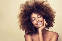 Beauty portrait of african american woman with clean healthy skin on beige background. Smiling beautiful afro girl.Curly black hair