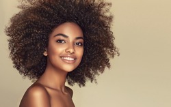 Beauty portrait of african american black  woman with clean healthy skin on beige background. Life style and cosmetic. Smiling beautiful afro girl.Curly  hair
