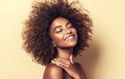 Beauty portrait of african american woman with clean healthy skin on beige background. Smiling dreamy beautiful afro haitstyle  girl.Curly black hair