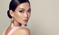 Asian model  fashion girl  with tassel earrings and  pink dress.