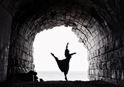 Dancer, graceful woman dancing in the arch, ballet dancer. ballerina dancing in the old fortification place. Contrast, silhouette of girl figure on sunny day. Woman figure. Black and white photo