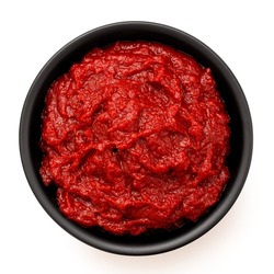 Tomato paste in a black ceramic bowl isolated on white. Top view.