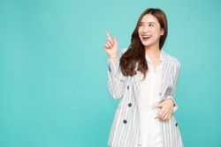 Young Asian woman smiling and pointing finger to empty copy space isolated on green background