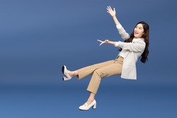 Happy cheerful young Asian businesswoman in suit floating in the air isolated on blue background, Presentation concept