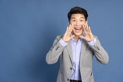Asian businessman with open mouths raising hands screaming announcement isolated on blue background
