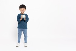 Portrait of happy Asian little boy holding sky blue piggy bank isolated on white background, Saving money and financial economize concept, Full body composition and five years old