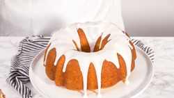 Step by step. Glazing a lemon bundt cake with white glaze on a cake stand.