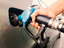 Hand holding gasoline nozzle for car refueling at gas station