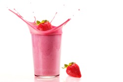 Fresh strawberries falling into a glass to make a delicious and healthy strawberry milkshake isolated on white background.