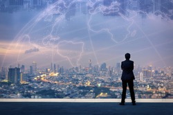 Vision concept. Successful businessman standing with hands crossed on chest, On top of building and looking through Cityscape Skyline Night Light.