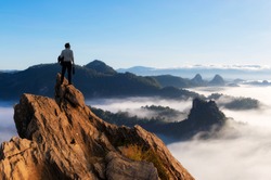 Concept vision, Young businessman wearing comfortable casual suit jacket standing holding business bag on top of peak mountain and looking forwards, success, competition and leader concept.