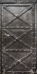 Old iron door reinforced with steel belts and rivets