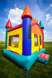 Bounce house inflatable jumpy castle in a large open yard.