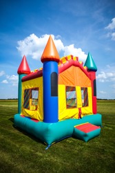 Children's bouncy house castle in a large open yard. 