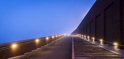 Modern architectural bridge and stairs on dike in Nijmegen over the Waal in the morning with fog, Netherlands.