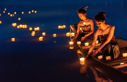 Young asian girls floating lanterns in the lake. The festival may originate from an ancient ritual praying respect to the water spirits.