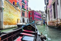 Gondola on the Venetian canal during the midday, tourists go sightseeing in Venice, Italy.