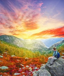 Woman traveler with backpack hiking in Norway mountains . Beautiful autumn sunset landscape near Stavanger , Lysefjord . Extreme travel background
