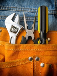 Work tools in orange tool bag with jeans.