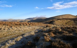 Views of The Cheviot in the distant centre with Windy Gyle on the right on a sunny winters morning in the Northumberland Cheviot mountains at sunrise, UK.