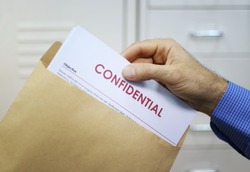Hand holding envelope with top secret confidential documents