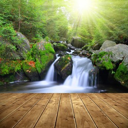 Waterfall on a mountain creek. In the foreground a wooden planks.