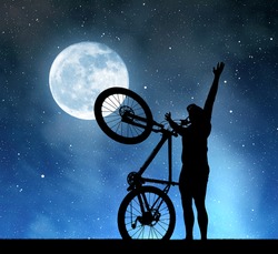 Silhouette of a man with a bicycle in the night sky with the moon.  