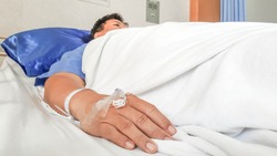 close up of saline solution preparation on hand of man patient lying on the hospital bed