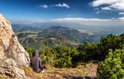 Tourist sitting on top of the hill Velky Choc and looking on beautiful mountain landscape in Slovakia.