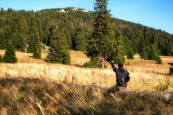 Hiker sitting on tree trunk and showing on hill Velky Choc in Slovakia. Hiking theme