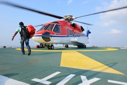 A passenger carry his baggage to embark helicopter at oil rig platform