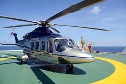 The helicopter park on oil rig platform to pick up worker with blue sky