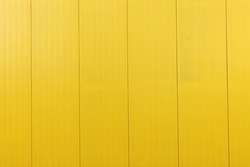 Yellow metal tile fence background. Fence from corrugated board. Yellow slate background. Yellow zinc metal sheet texture. Steel panel of the enclosing wall.