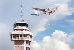 Air traffic control tower in international airport with passenger airplane jet taking off in the background