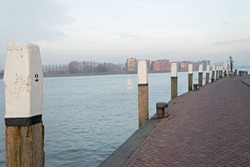 Quay along the Nieuwe Merwede with wooden bollard poles with white top in Dordrecht, the Netherlands