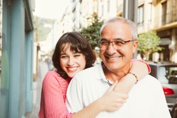 Portrait of a mature father with his young daughter laughing on the street. Focus on him