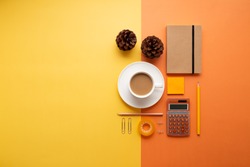 Office or school supplies with coffee cup and pine cones on an orange and yellow background. Flat lay. Back to office or school concept